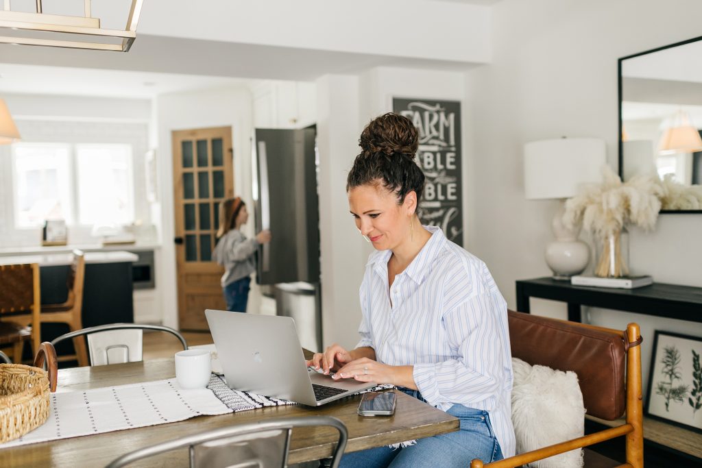 Mom working at home with kid in background at fridge